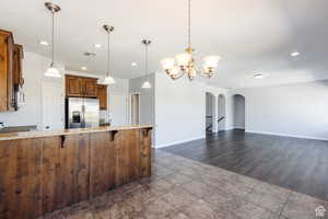 Kitchen with a breakfast bar, recessed lighting, stainless steel fridge with ice dispenser, light stone counters, and pendant lighting