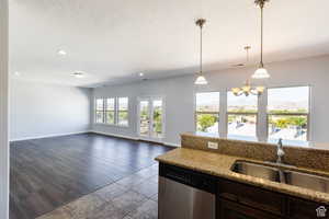 Kitchen with dishwasher, a chandelier, a textured ceiling, decorative light fixtures, and light stone countertops