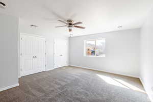Unfurnished bedroom with carpet floors, two closets, a textured ceiling, and a ceiling fan