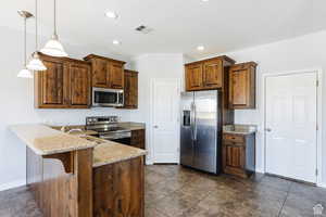 Kitchen featuring stainless steel appliances, a peninsula, light stone countertops, decorative light fixtures, and recessed lighting