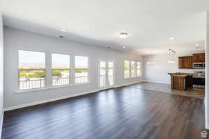 Unfurnished living room with dark wood finished floors, a chandelier, recessed lighting, a textured ceiling, and french doors