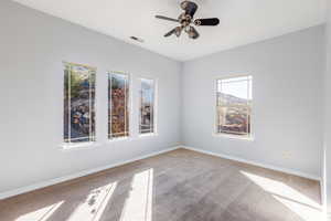 Carpeted empty room featuring ceiling fan and baseboards