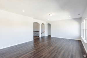 Spare room featuring dark wood finished floors, recessed lighting, and arched walkways