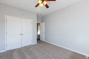 Unfurnished bedroom with carpet floors, a closet, and ceiling fan