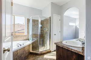 Bathroom featuring a shower stall, a garden tub, and vanity