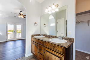 Full bathroom with double vanity, ceiling fan, french doors, and a spacious closet