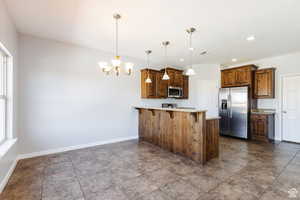 Kitchen with stainless steel appliances, a chandelier, a peninsula, a breakfast bar area, and pendant lighting