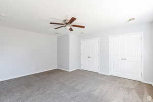 Unfurnished bedroom featuring carpet floors, multiple closets, and ceiling fan