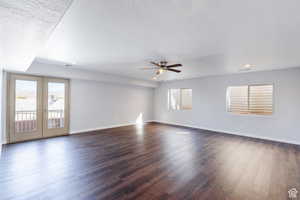Empty room with healthy amount of natural light, a ceiling fan, dark wood-style floors, a textured ceiling, and recessed lighting