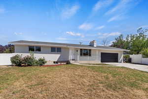 Single story home with brick siding, a chimney, an attached garage, concrete driveway, and covered porch
