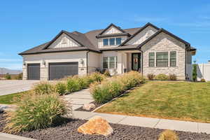View of front facade featuring board and batten siding, an attached garage, driveway, stone siding, and roof with shingles