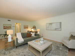 Living area with wood finished floors and ornamental molding