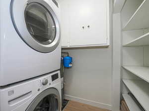 Laundry room with stacked washer and clothes dryer and light wood finished floors