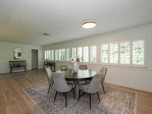 Dining room with crown molding, wood finished floors, and a wainscoted wall