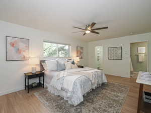 Bedroom featuring light wood finished floors, a ceiling fan, and ensuite bathroom