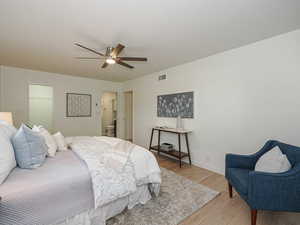 Bedroom featuring light wood-type flooring, connected bathroom, and ceiling fan