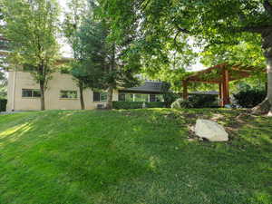 View of grassy yard featuring a pergola