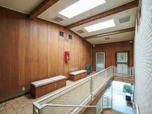 Hallway featuring wood walls and tile patterned floors