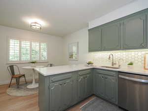 Kitchen featuring a peninsula, dishwasher, light countertops, backsplash, and light wood finished floors