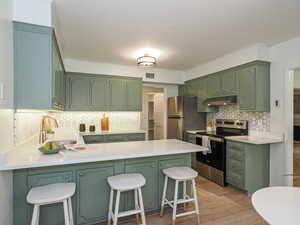 Kitchen with green cabinetry and a peninsula