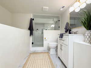 Bathroom with vanity, a stall shower, and tile walls