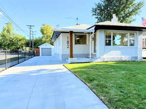 Bungalow-style house featuring a garage, an outbuilding, brick siding, a chimney, and driveway