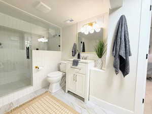 Bathroom with vanity, a shower stall, and tile walls