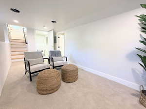 Sitting room with light colored carpet, stairs, and recessed lighting