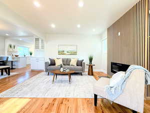 Living room featuring light wood-style floors, recessed lighting, and a glass covered fireplace