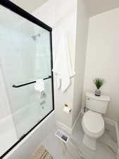 Full bath with toilet and combined bath / shower with glass door