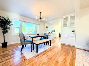 Dining room with healthy amount of natural light, a chandelier, and light wood-style flooring