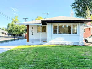 Bungalow featuring driveway, brick siding, covered porch, and a chimney