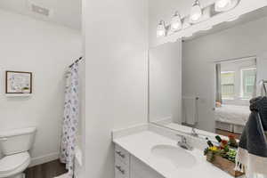 Ensuite bathroom featuring vanity, shower / bathtub combination with curtain, and wood finished floors