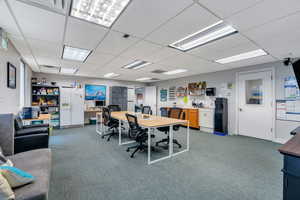 Home office with a paneled ceiling and carpet
