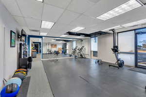 Exercise room with a drop ceiling and baseboards