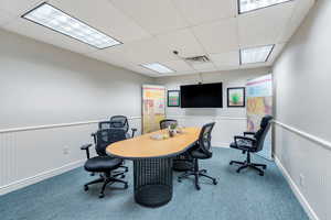 Carpeted office featuring wainscoting and a paneled ceiling