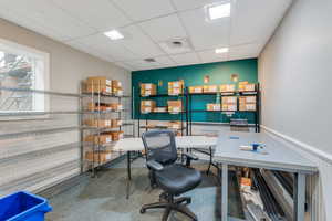 Office space featuring a drop ceiling and a wainscoted wall