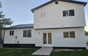 Rear view of property featuring a metal roof and a yard