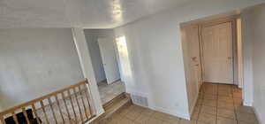 Corridor featuring a textured ceiling and light tile patterned floors