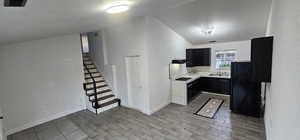Kitchen with a textured ceiling, freestanding refrigerator, light countertops, wood tiled floors, and lofted ceiling