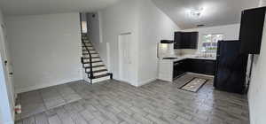 Kitchen featuring vaulted ceiling, light countertops, freestanding refrigerator, dark cabinetry, and a textured ceiling