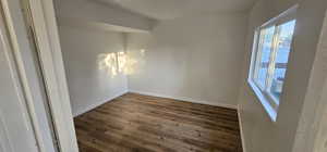 Unfurnished room with dark wood-style floors and baseboards
