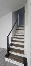 Stairs with wood finished floors and a textured ceiling