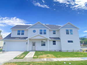 View of front of house with a garage, concrete driveway, and a front lawn