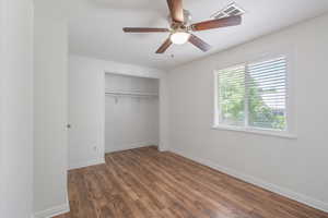Unfurnished bedroom with laminate floors, a closet, and a ceiling fan