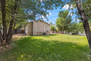 View of fenced backyard with large mature shade trees