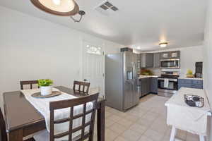 Kitchen featuring stainless steel appliances, gray cabinetry, light countertops, and light tile patterned floors