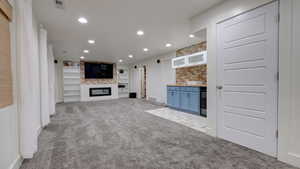 Unfurnished living room with light carpet, a fireplace, recessed lighting, beverage cooler, and bar area