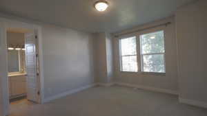 Unfurnished bedroom featuring light colored carpet and connected bathroom