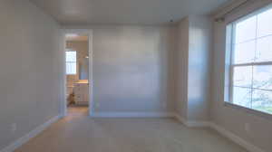Spare room with baseboards and light carpet